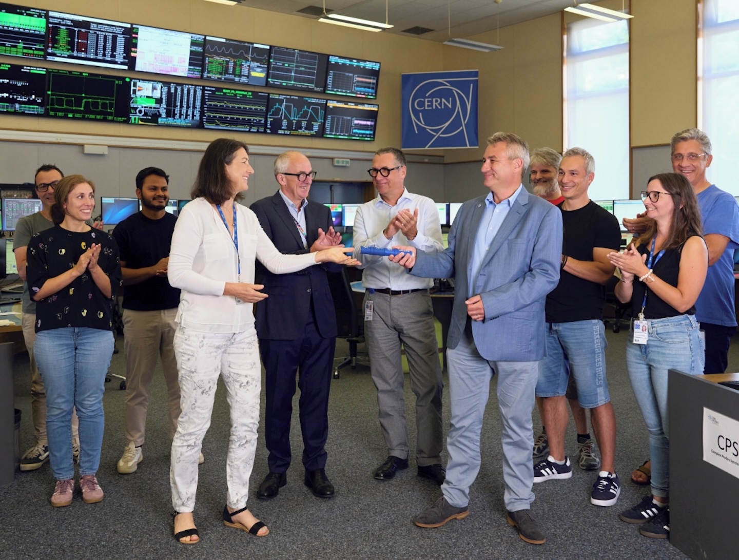 Bettina Mikulec, Leader of CERN’s Operations Group (left), hands over the baton – symbolised by a miniature superconducting magnet from the LHC – to Jean-Philippe Tock, Head of the LS3 Coordination Team (right), in front of Mark Thomson, CERN Director-General (second from left), and Oliver Brüning, CERN Director for Accelerators and Technology (third from left). (Image: CERN)